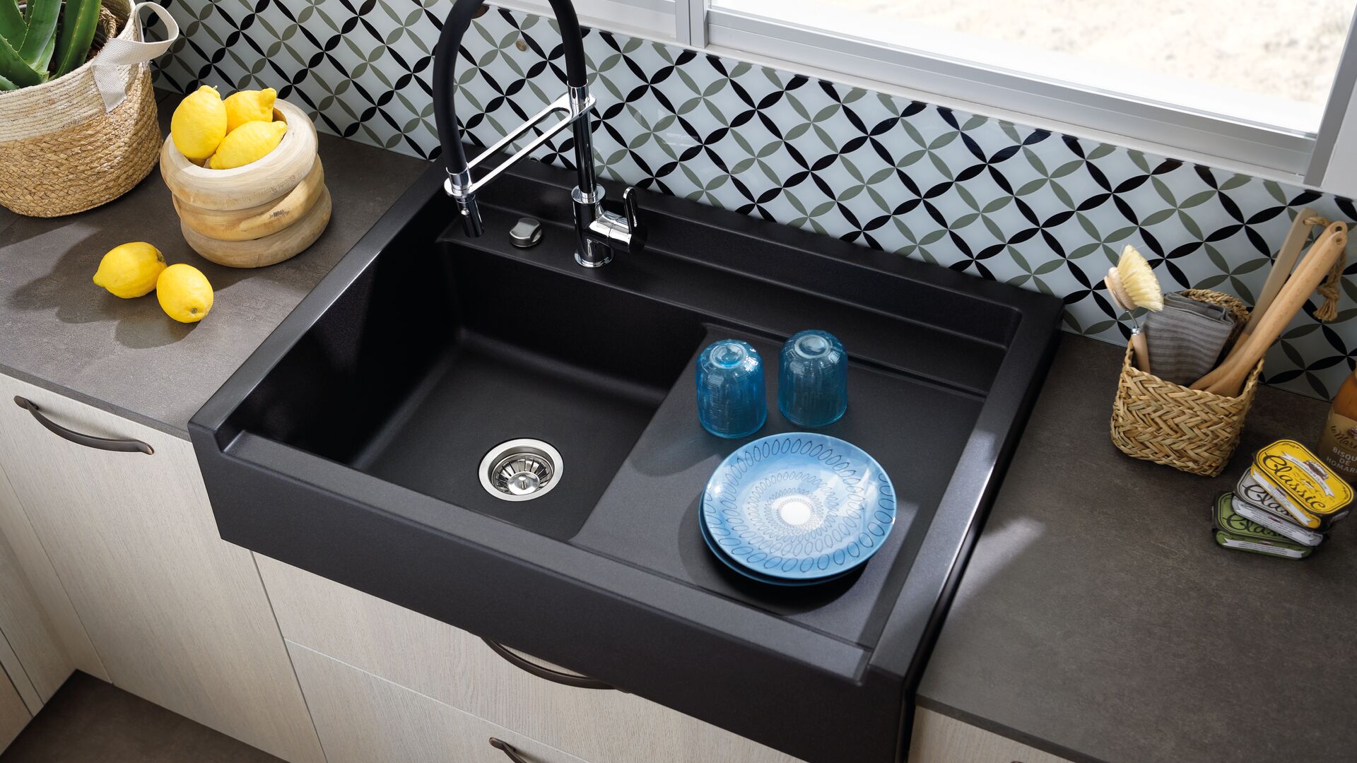 évier timbre d’office noir avec mitigeur douchette, plan de travail gris, façade couleur bois et crédence en verre