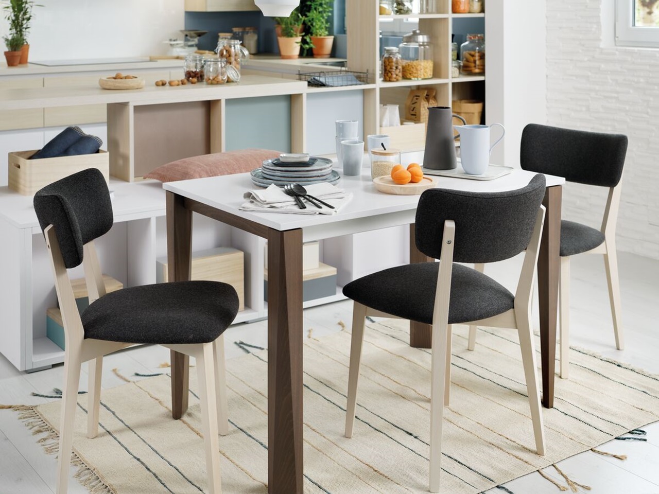 Ess-Ecke mit weißem Tisch mit marronfarbigen Füßen und Stühlen mit Holz und schwarz