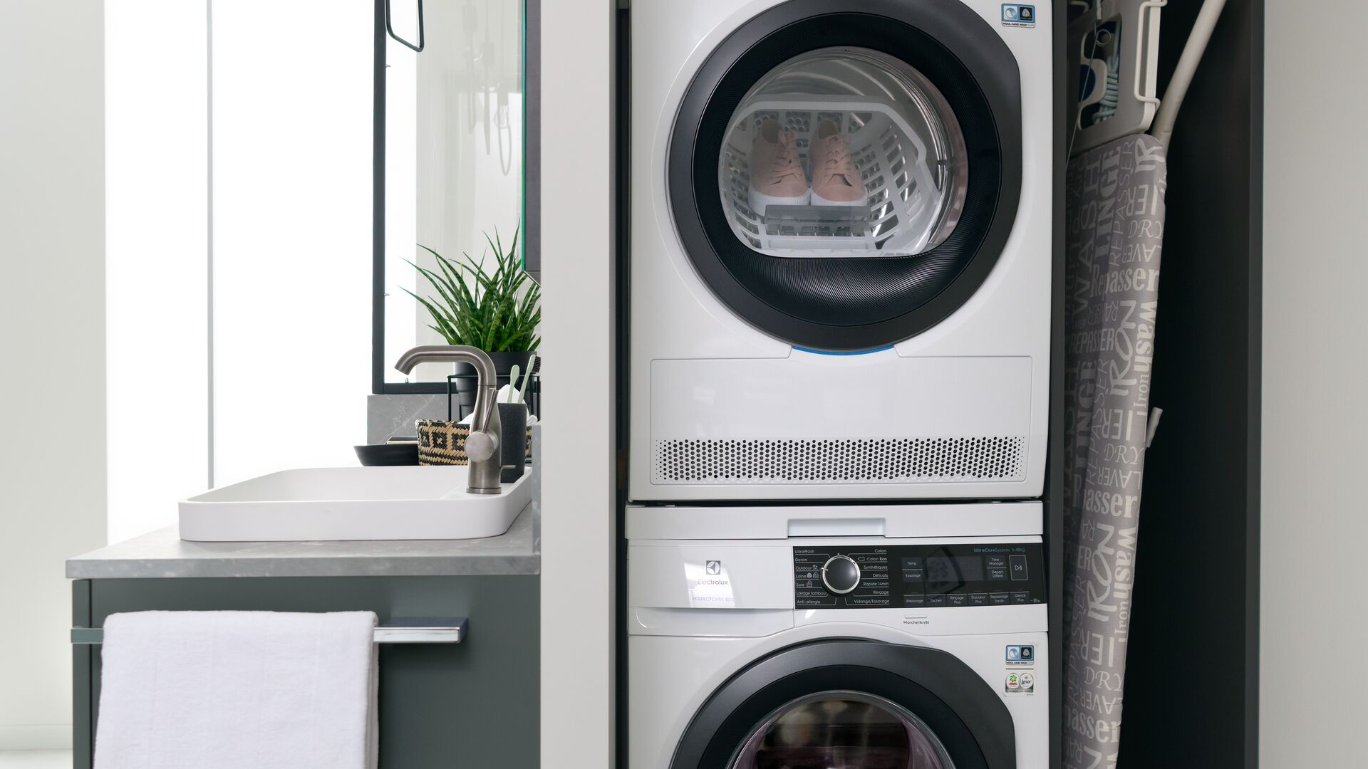 Schrank mit versteckter Waschkücheneinheit mit Waschmaschine und daraufgesetztem Trockner und Bügelbrett