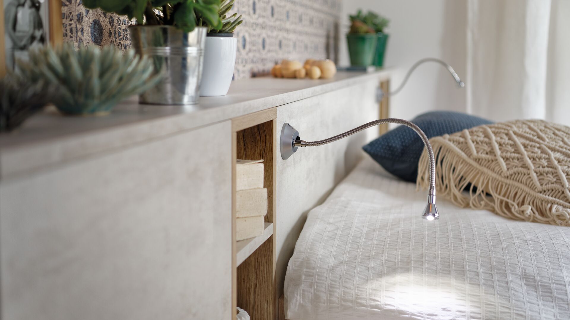 Vue de détail d'ambiance du rangement Arcos melaminé en coloris beige clair, cadrée sur le meuble tête de lit et les lampes intégrées
