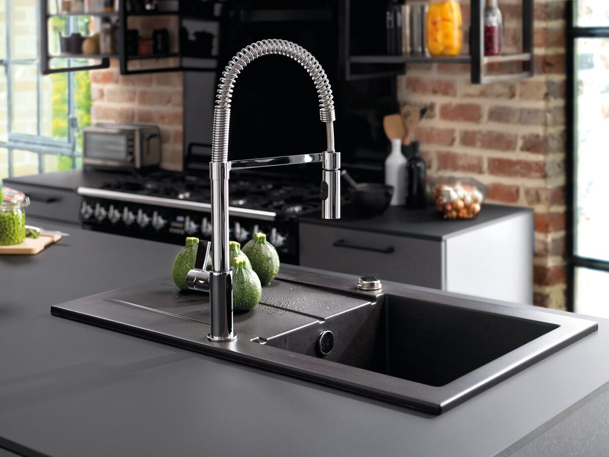 Vista general del fregadero de granito negro y del grifo mezclador de resorte con calabacines redondos colocados en el escurridor