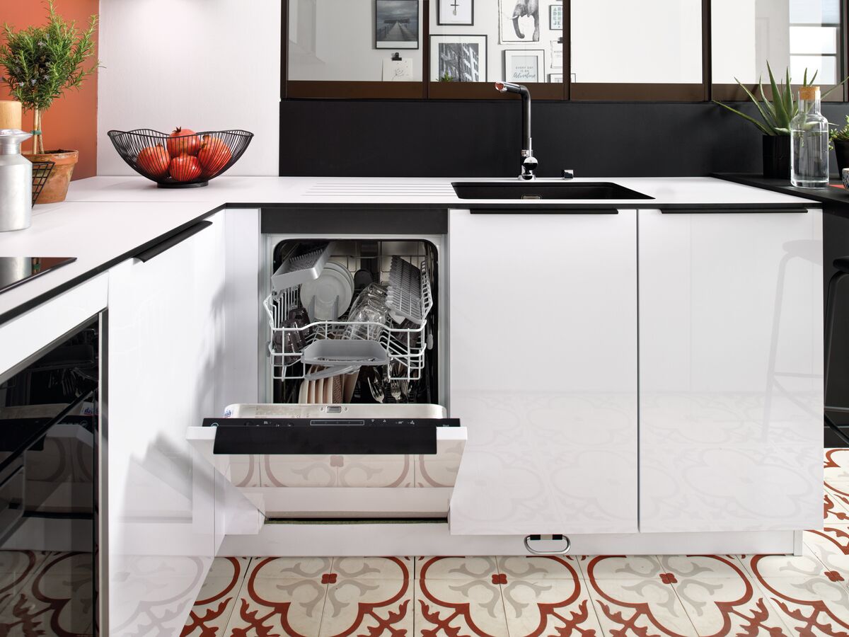 Vue des meubles bas blancs avec lave vaisselle ouvert, évier et mitigeur